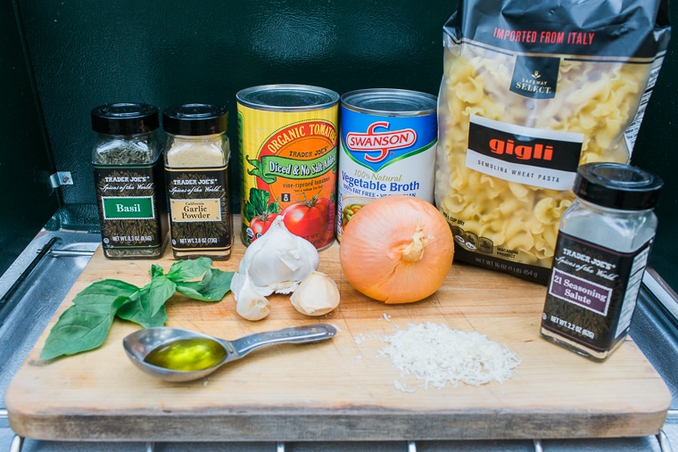 Ingredients for one pot pasta lined up on a wooden cutting board