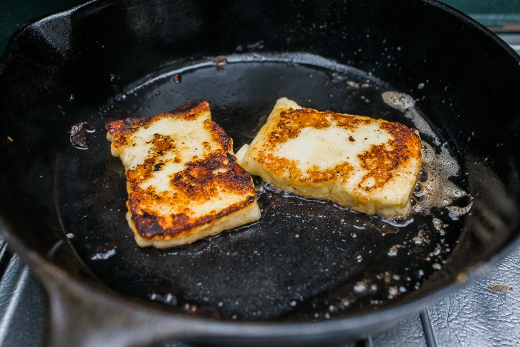Pieces of halloumi cooking in a skillet
