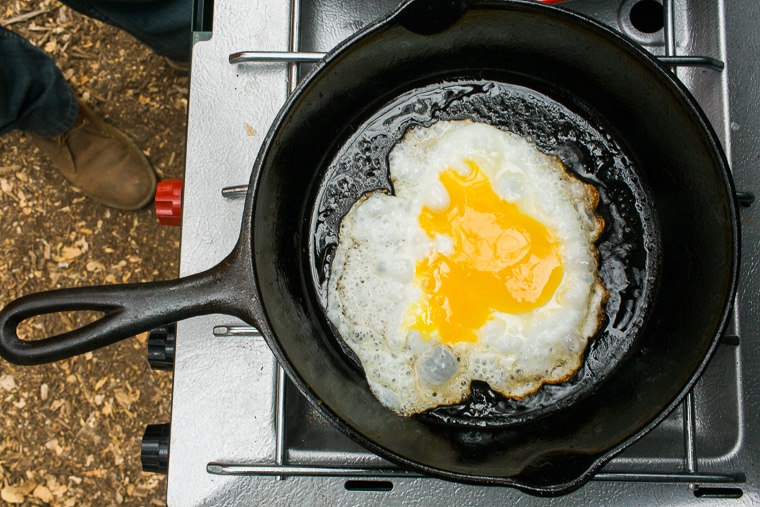 An egg frying in a cast iron skillet