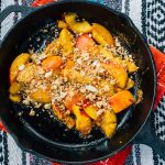 Peach crisp in a cast iron skillet on a table