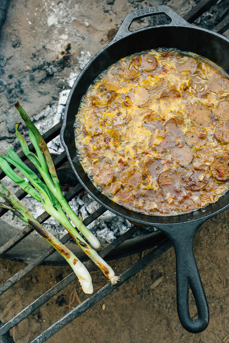Paella cooking in a cast iron skillet over a campfire