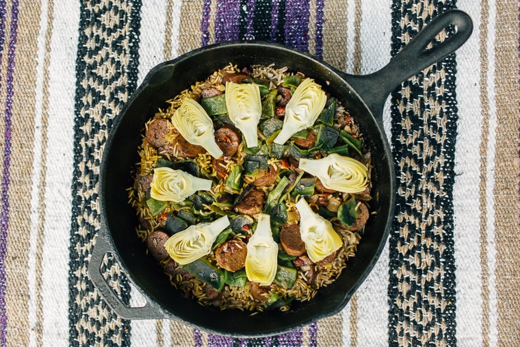 Paella cooking in a cast iron skillet over a campfire