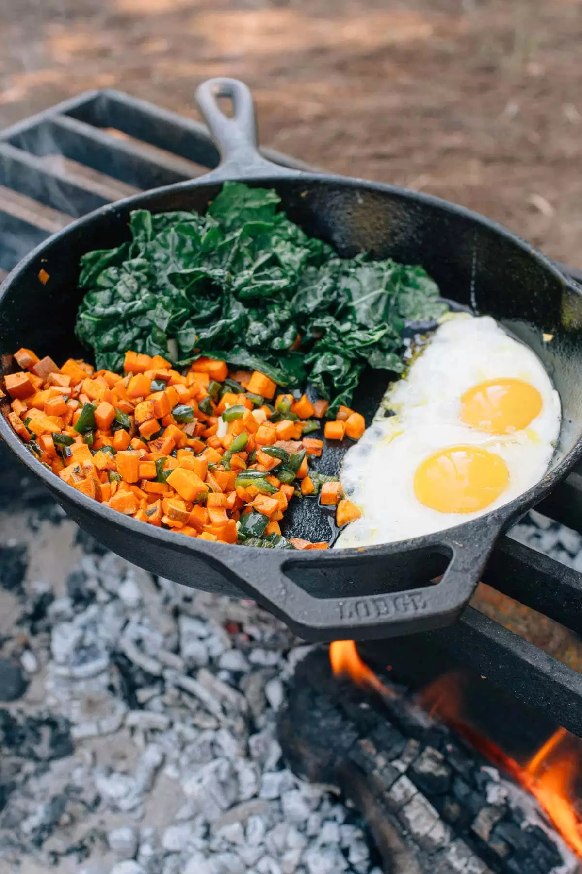 Breakfast hash and eggs in a cast iron skillet over a campfire