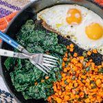 Cast-iron skillet with kale sweet potatoes and two eggs