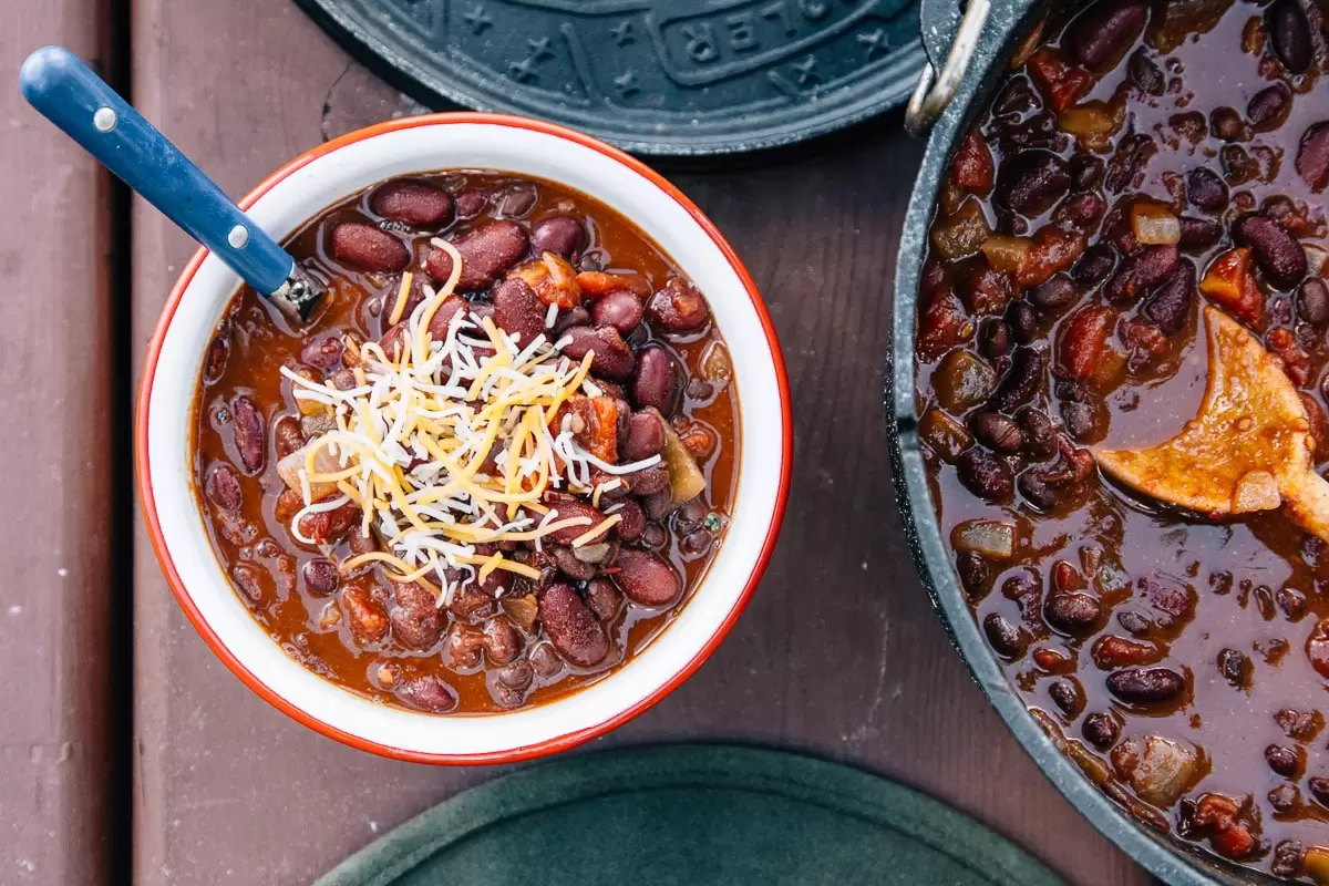 Chili topped with cheese in a red and white bowl