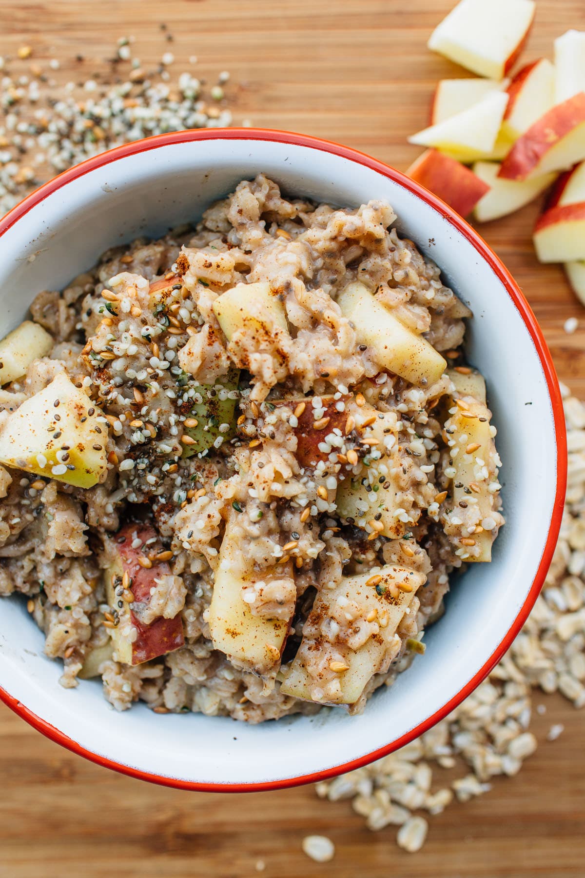 Apple spiced oatmeal and seeds in a white and red camping bowl.