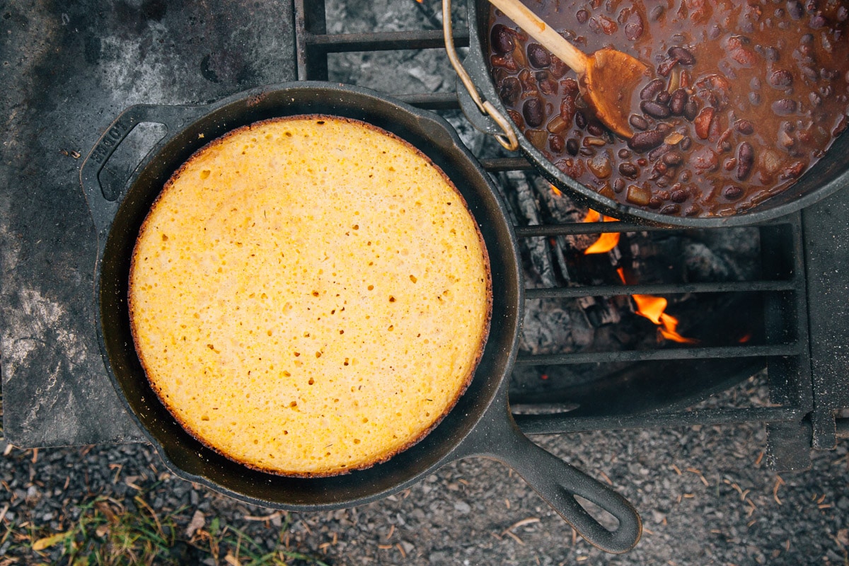 Cast iron skillet cornbread cooking on a campfire
