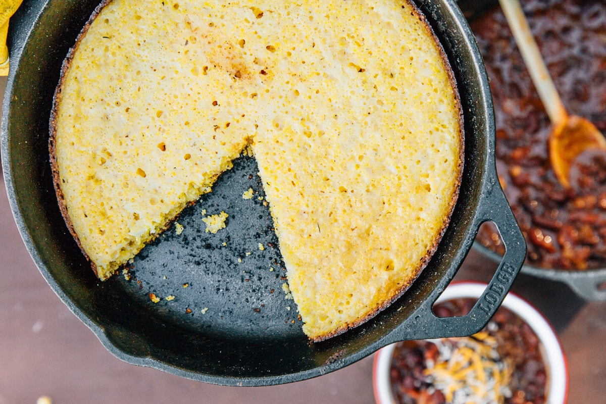 Cornbread in a cast iron skillet with a piece cut out