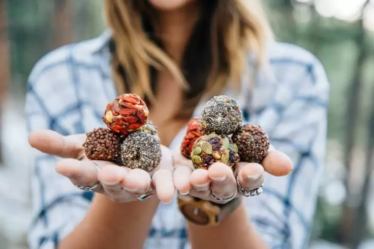 Woman holding a stack of trail mix bliss balls