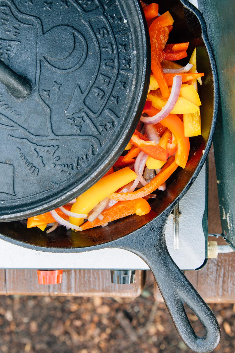 Veggies cooking in a cast iron skillet with a lid