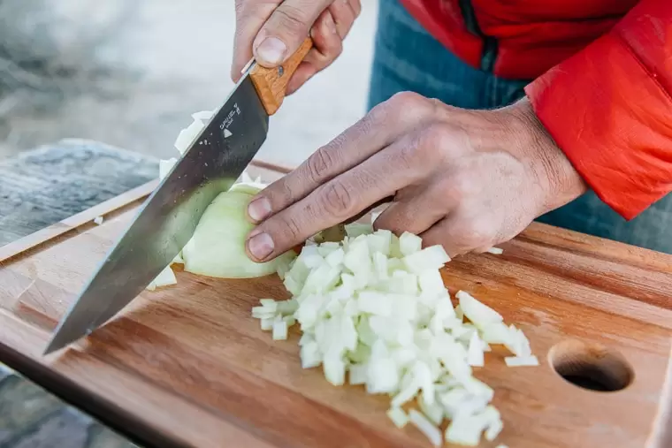 Michael chopping an onion on a wooden cutting board