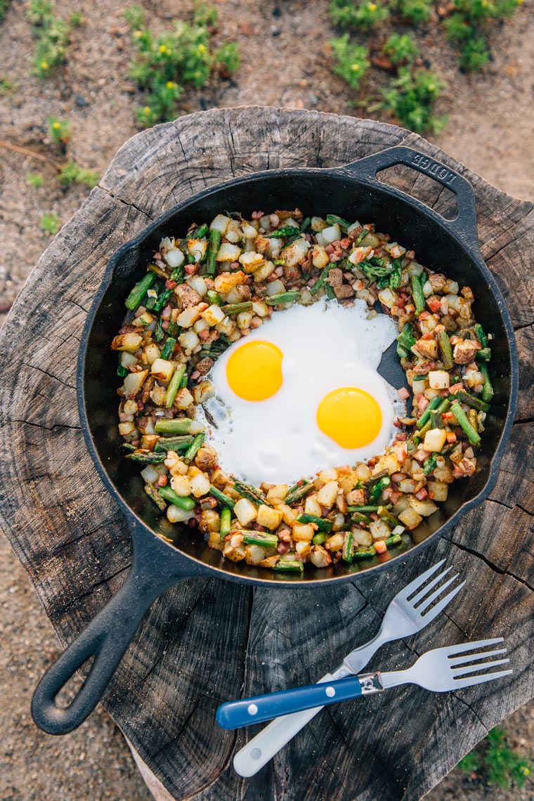 Potato hash with asparagus and two eggs in a cast iron skillet