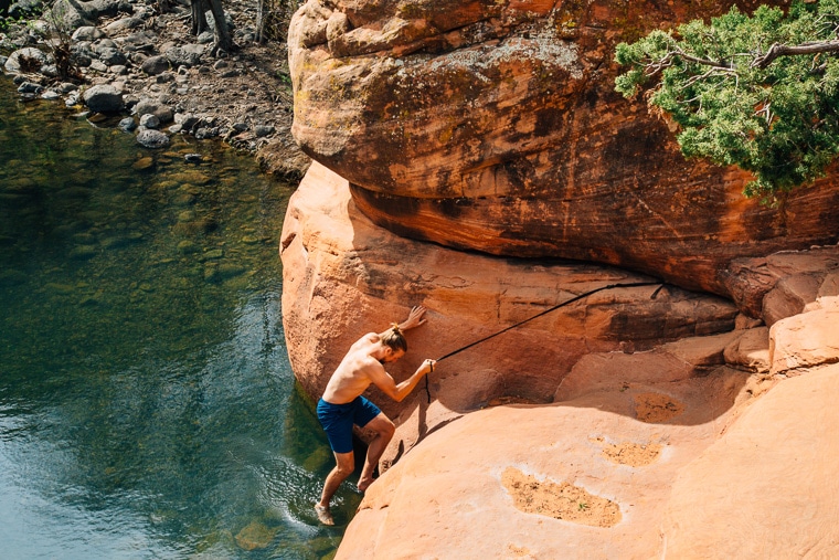 Michael using a rope to climb into the crack swimming hole in Sedona