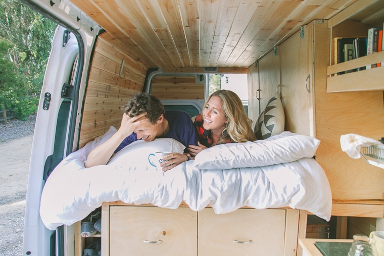 A man and a woman on the bed of their camper van