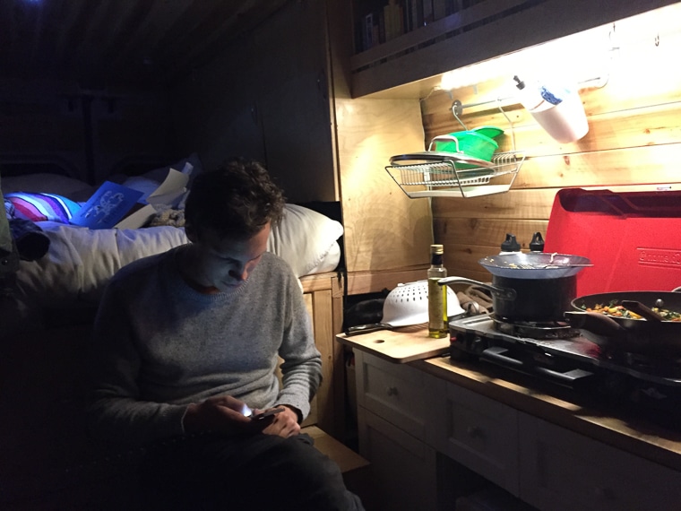 A man sitting next to a camp stove in a camper van