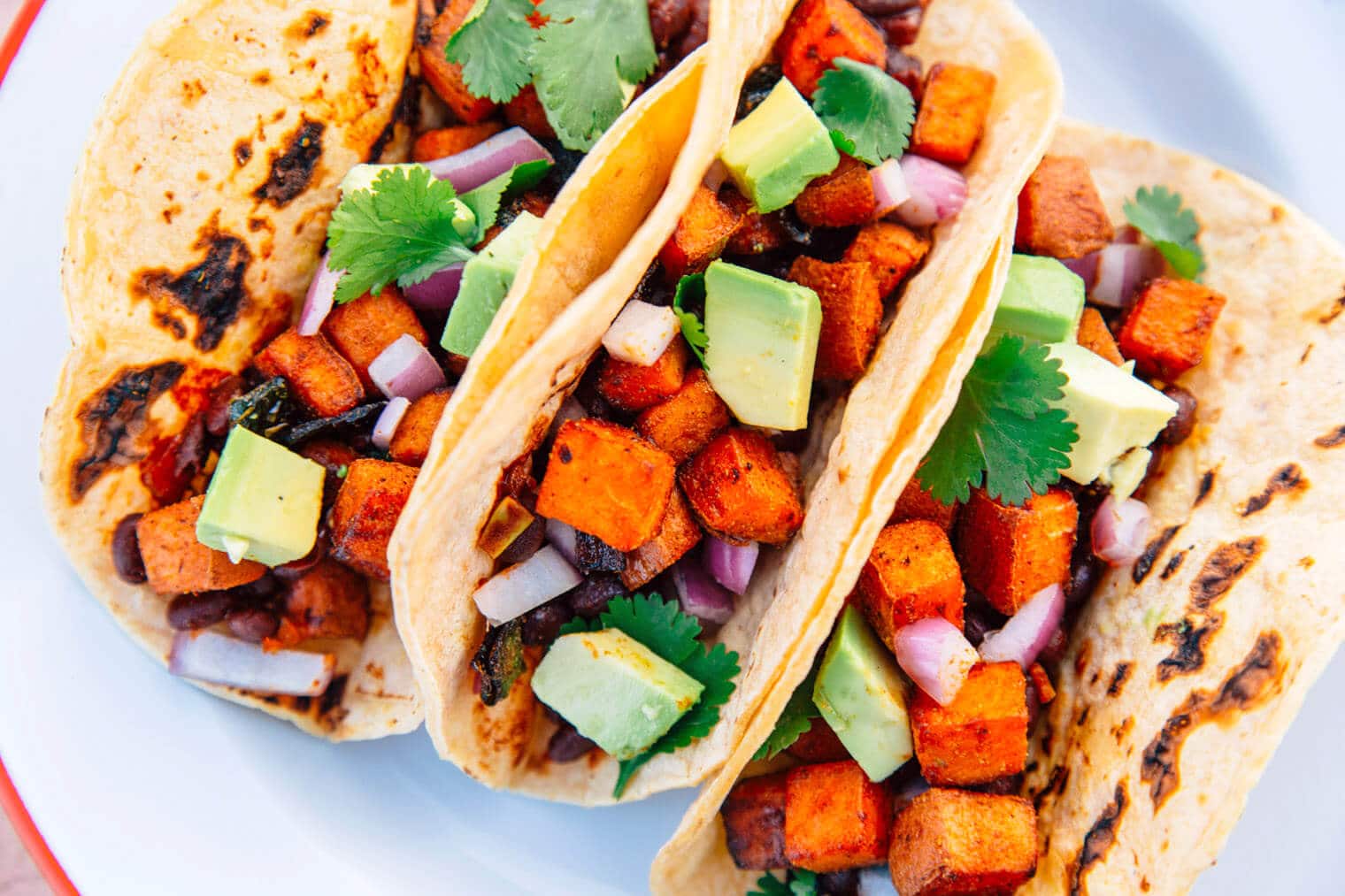 Three sweet potato and black bean tacos on a plate