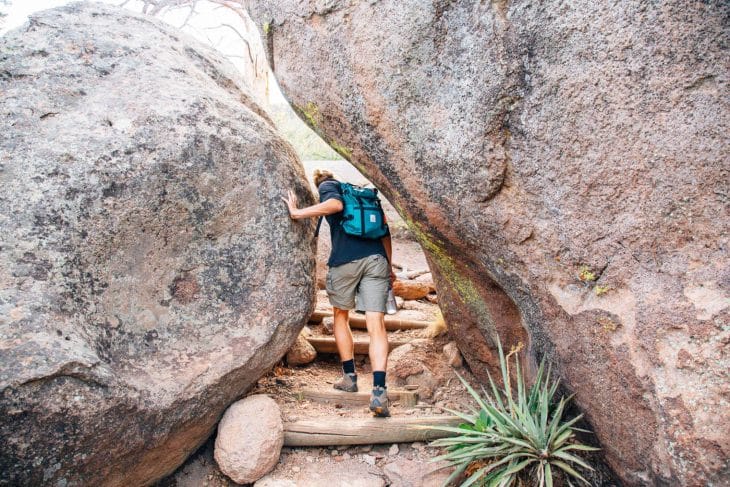Michael navigating between two large boulders on a trail