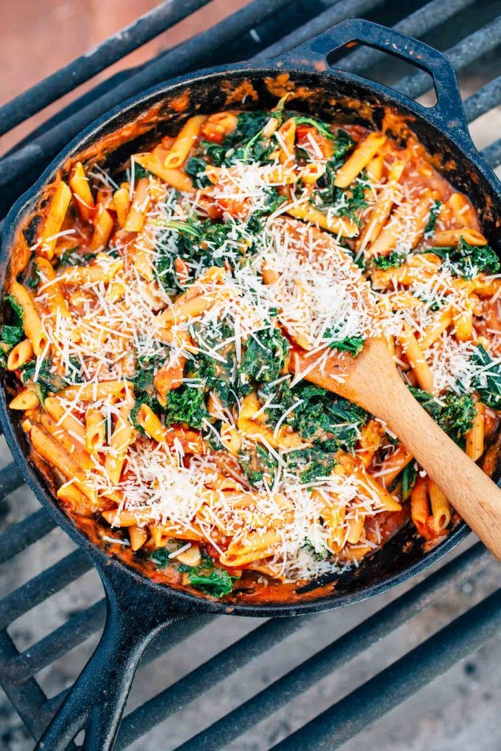 Pasta topped with cheese in a cast iron skillet over a campfire