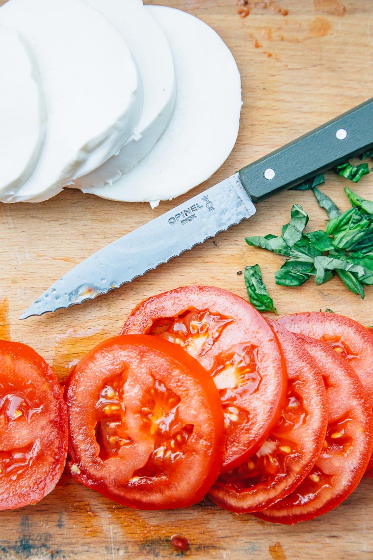 Mozzarella and tomato slices next to chopped basil
