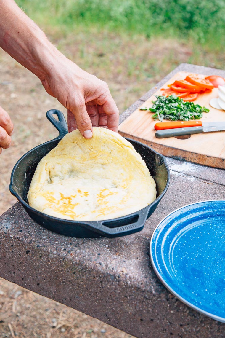 Michael flipping pizza dough in a cast iron skillet