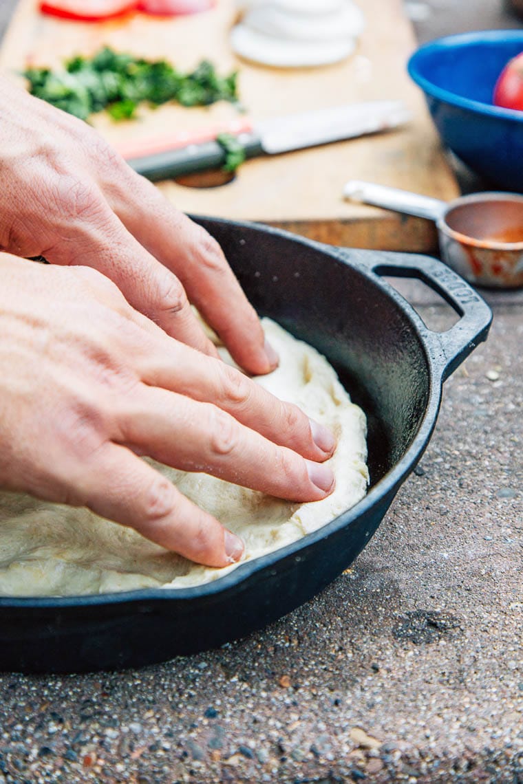 Michael stretching out pizza dough into a cast iron skillet