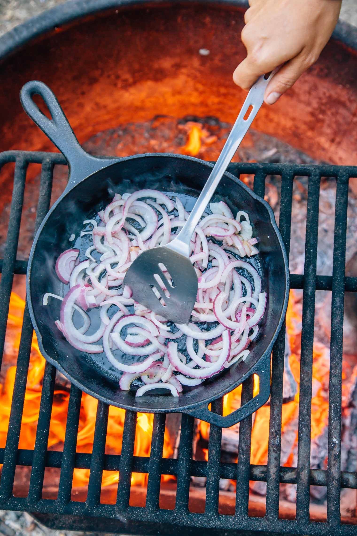 Sliced onions in a cast iron skillet over a campfire