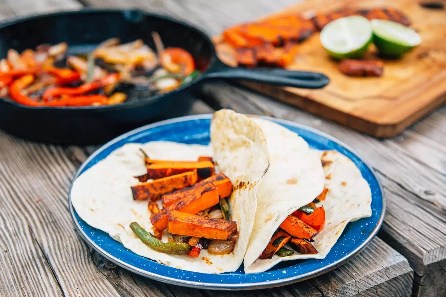Fajitas filled with sweet potatoes, roasted peppers and onions on a blue plate