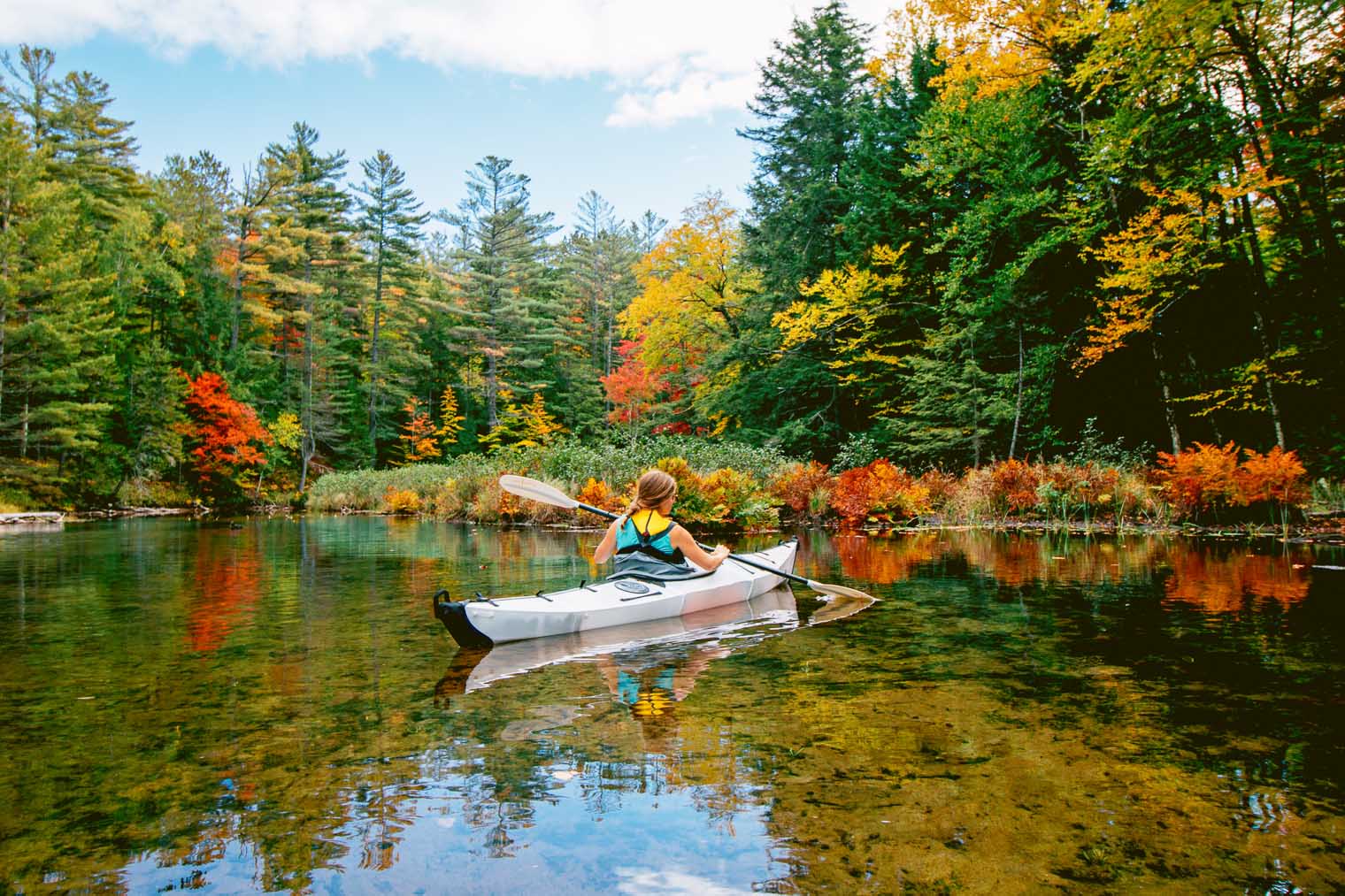 Megan kayaking with fall foliage around