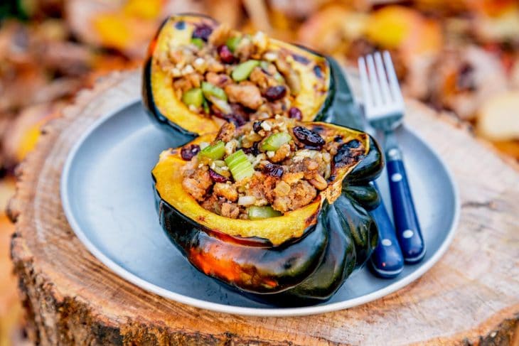 Two hands of an acorn squash that is stuffed with stuffing