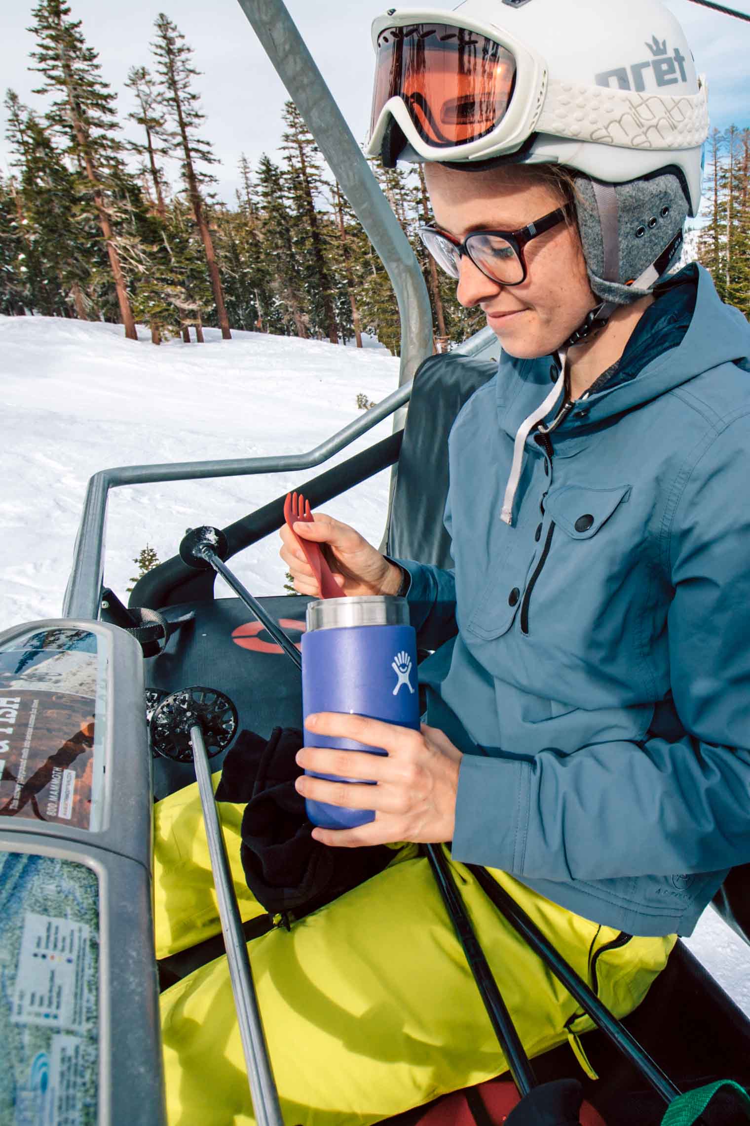 Megan eating from a insulated food container while on a ski lift