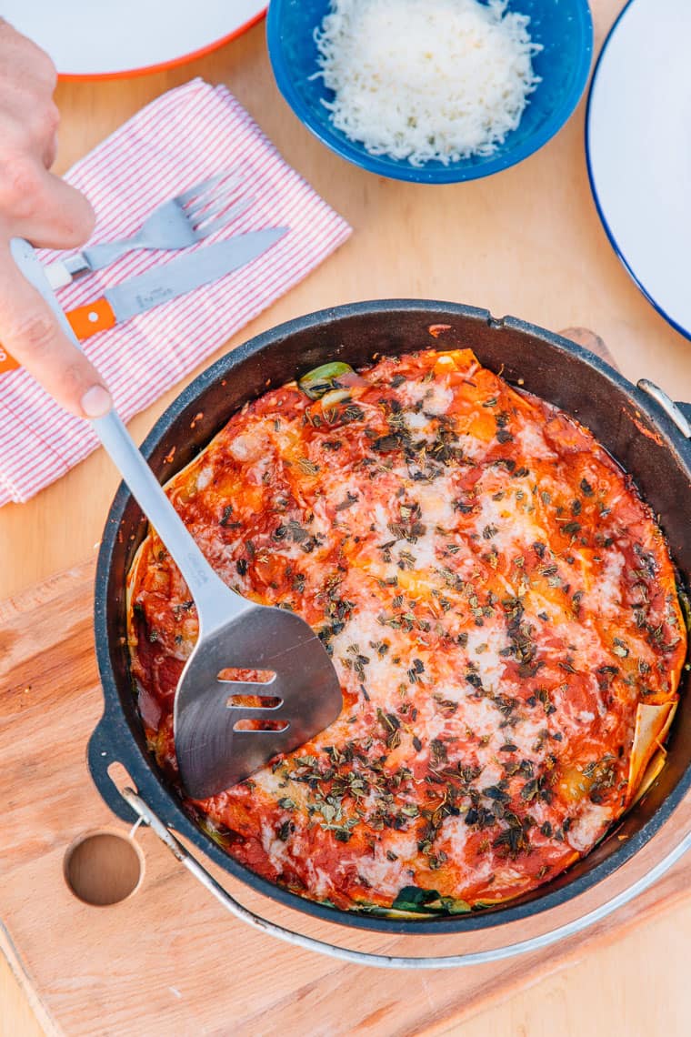 Dutch oven lasagna on a wooden camping table.