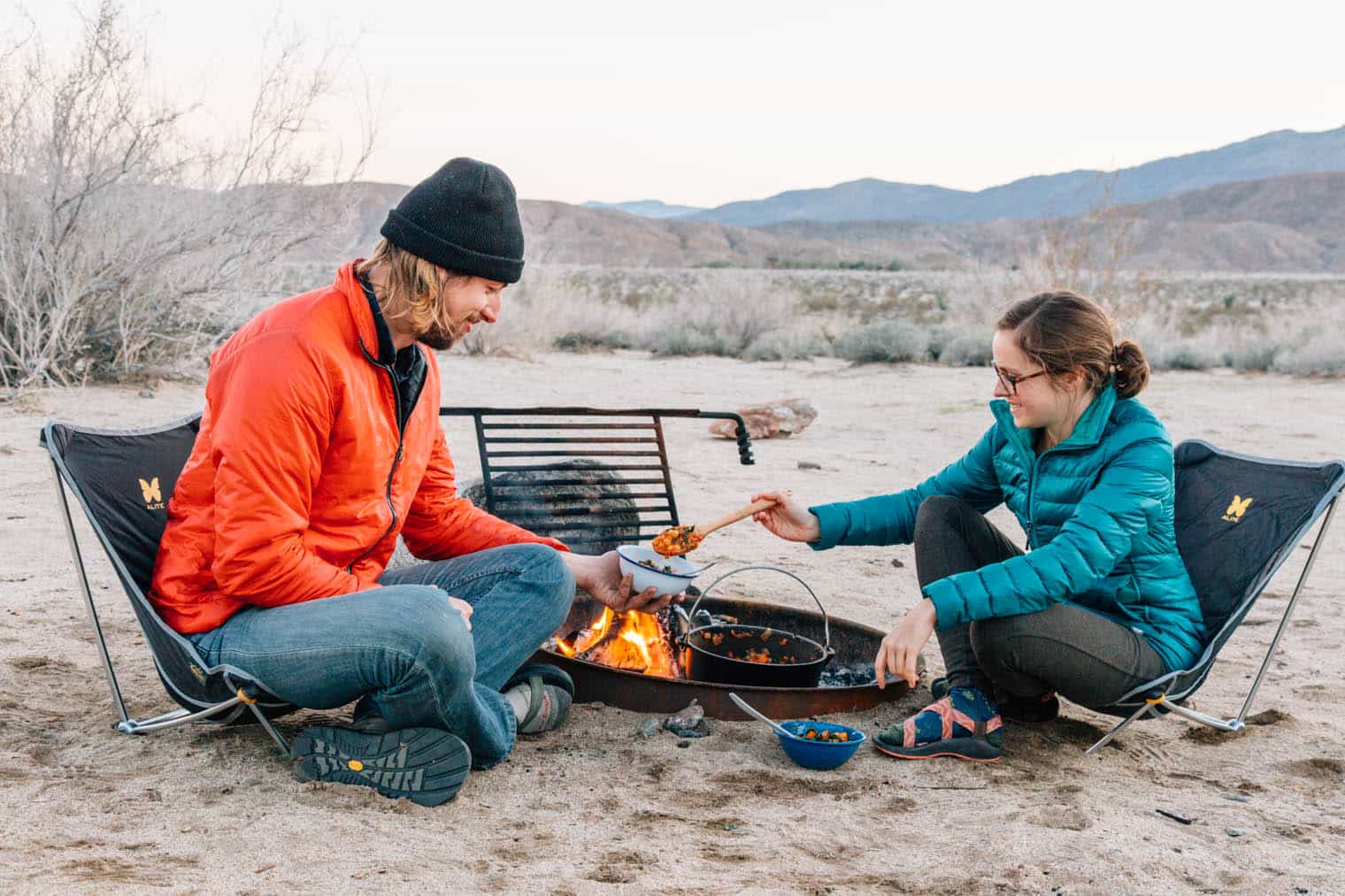 Megan and Michael sitting by a campfire Megan is serving Michael food from a Dutch oven