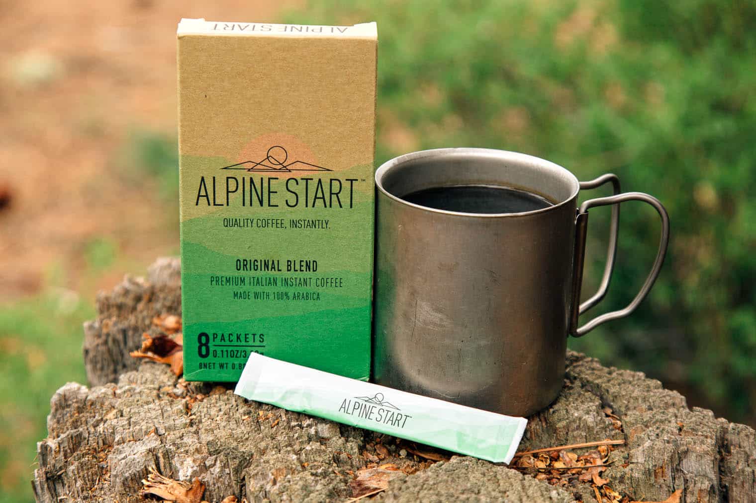 Alpine Start instant coffee packaging next to a camp mug