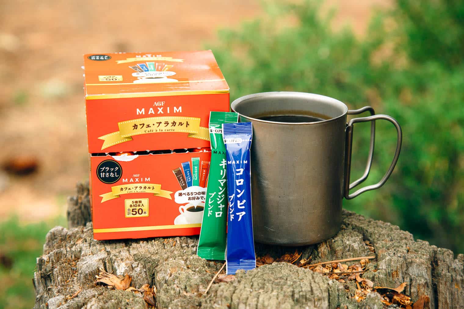Maxim  instant coffee packaging next to a camp mug
