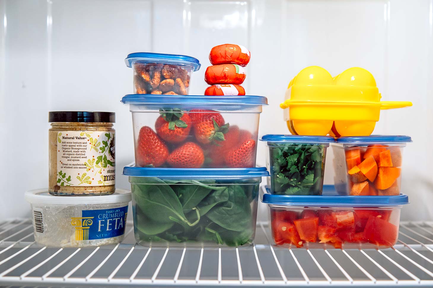 Watertight containers of food stacked on a refrigerator shelf.
