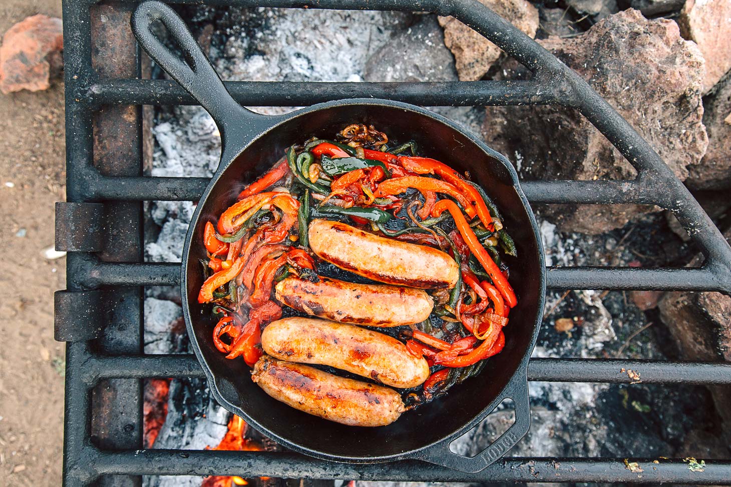 Cast Iron Brats are an easy campfire meal. Topped with sweet & spicy peppers and onions, this is a great, cheap dinner while camping.