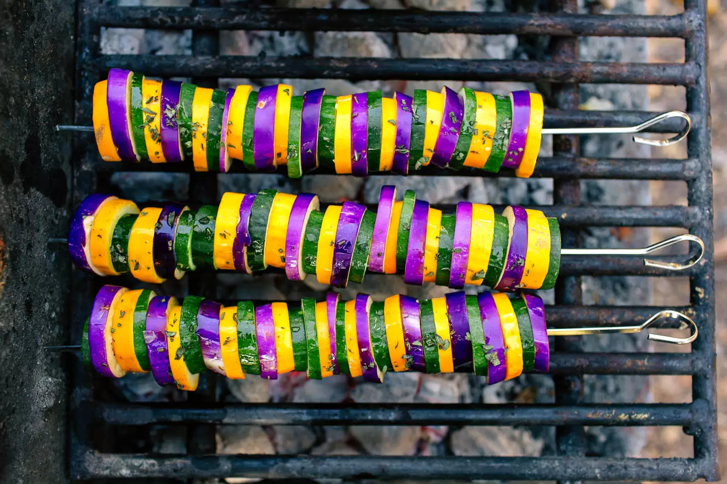 Ratatouille kabobs grilling over a campfire.
