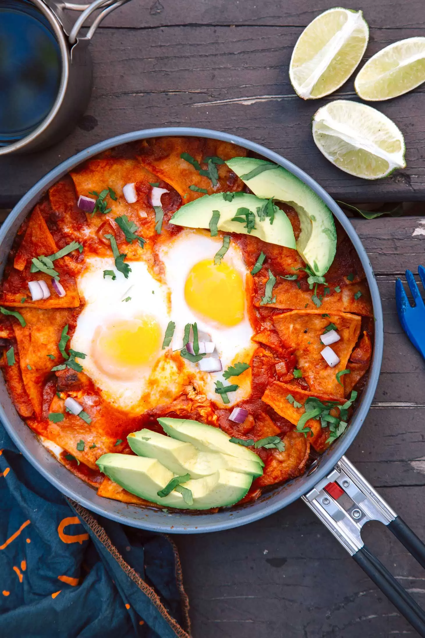 Chilaquiles with eggs and avocados in a pan on a camping table.