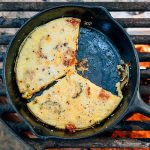Frittata in a cast iron skillet on a campfire