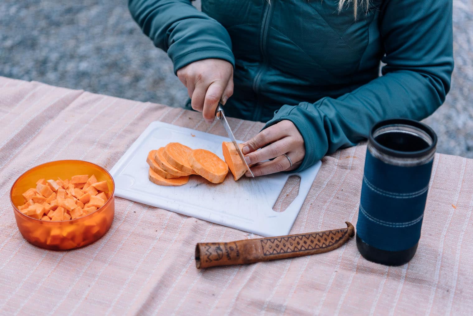 Woman slicing sweet potatoes on a white cutting board