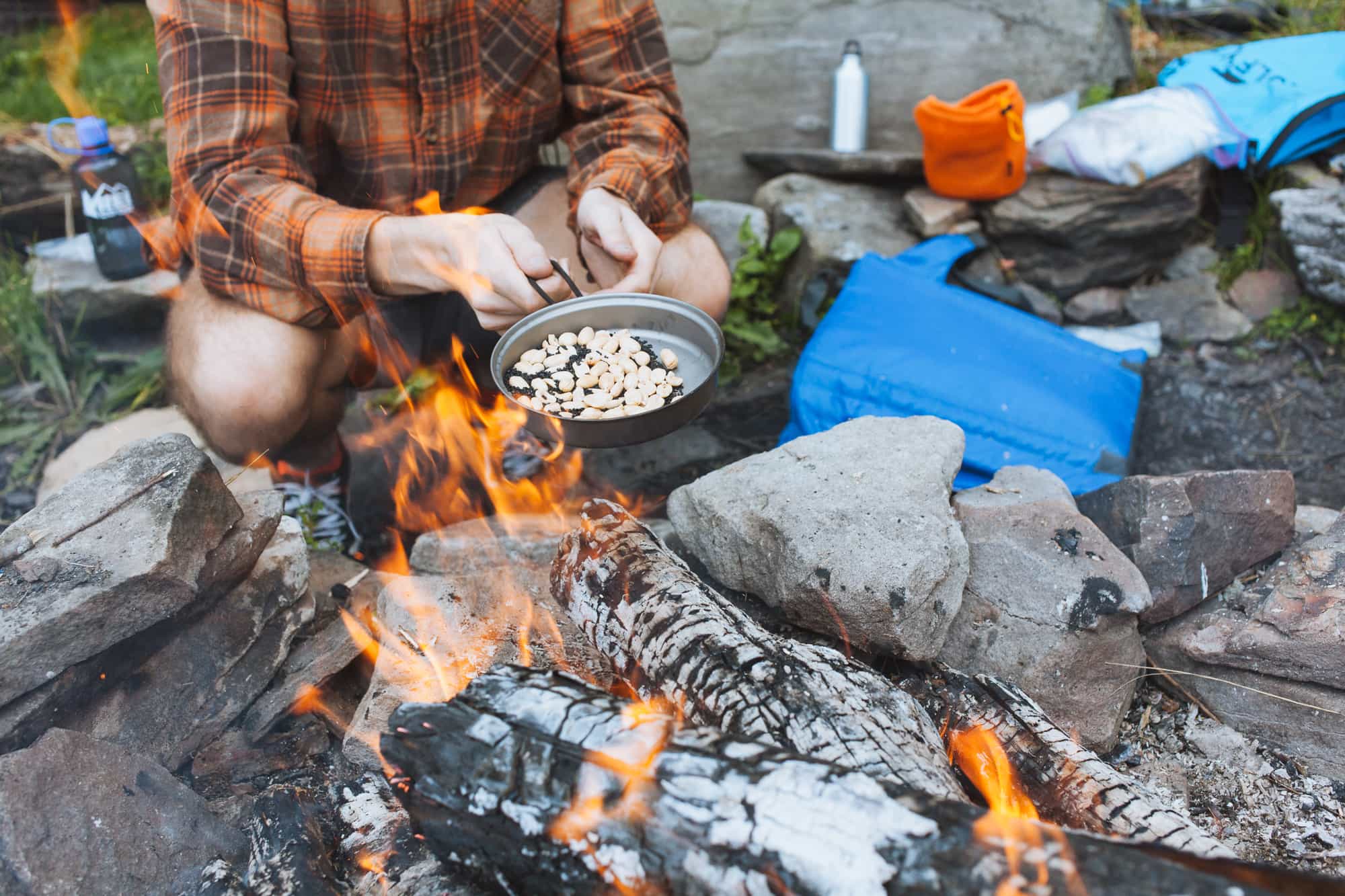 Man cooking with a small pan over a campfire