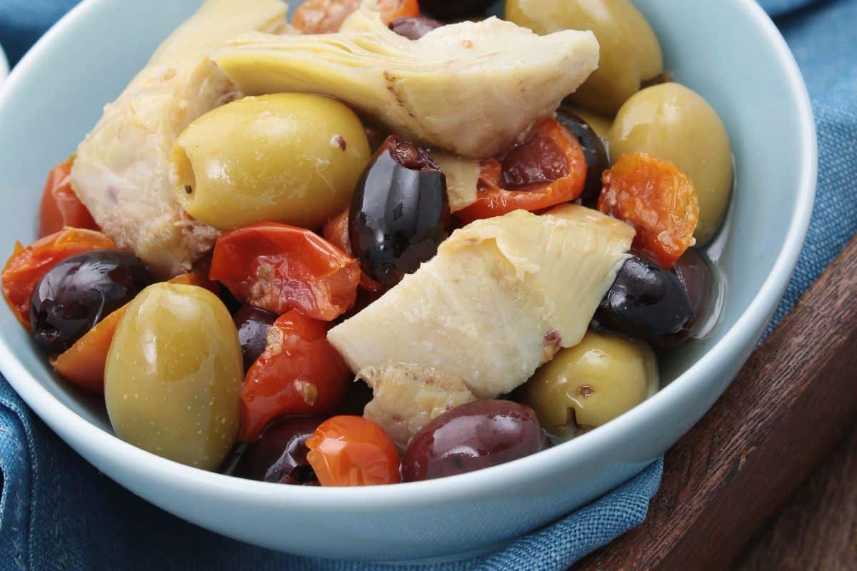 Olives, artichoke hearts, and sliced tomatoes in a bowl.