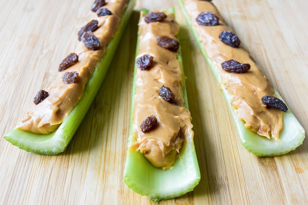 Three celery sticks topped with peanut butter and raisins.