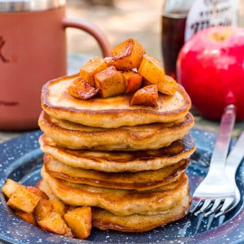 A stack of apple pancakes on a plate, topped with chopped apples.