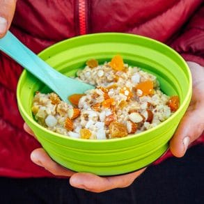 Man holding a green backpacking bowl full of apricot ginger oatmeal