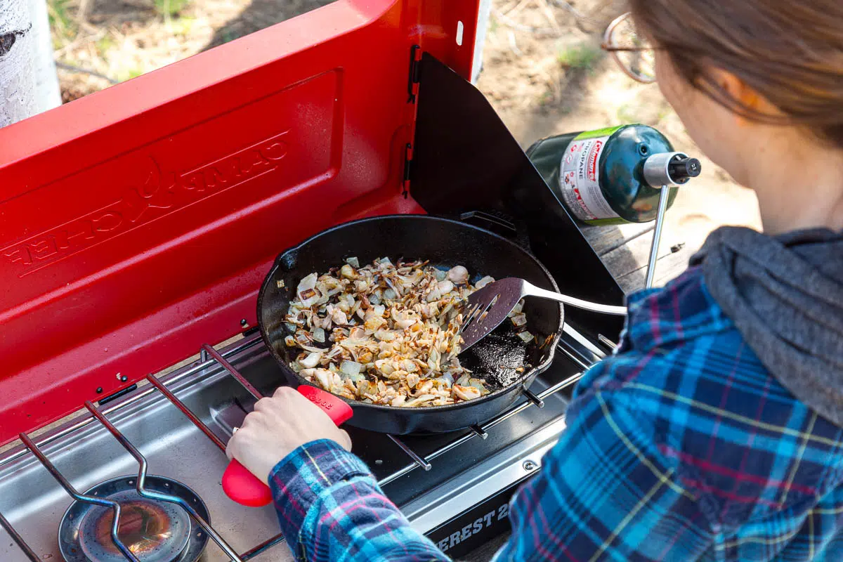 Megan cooking jackfruit in a skillet on a camping stove