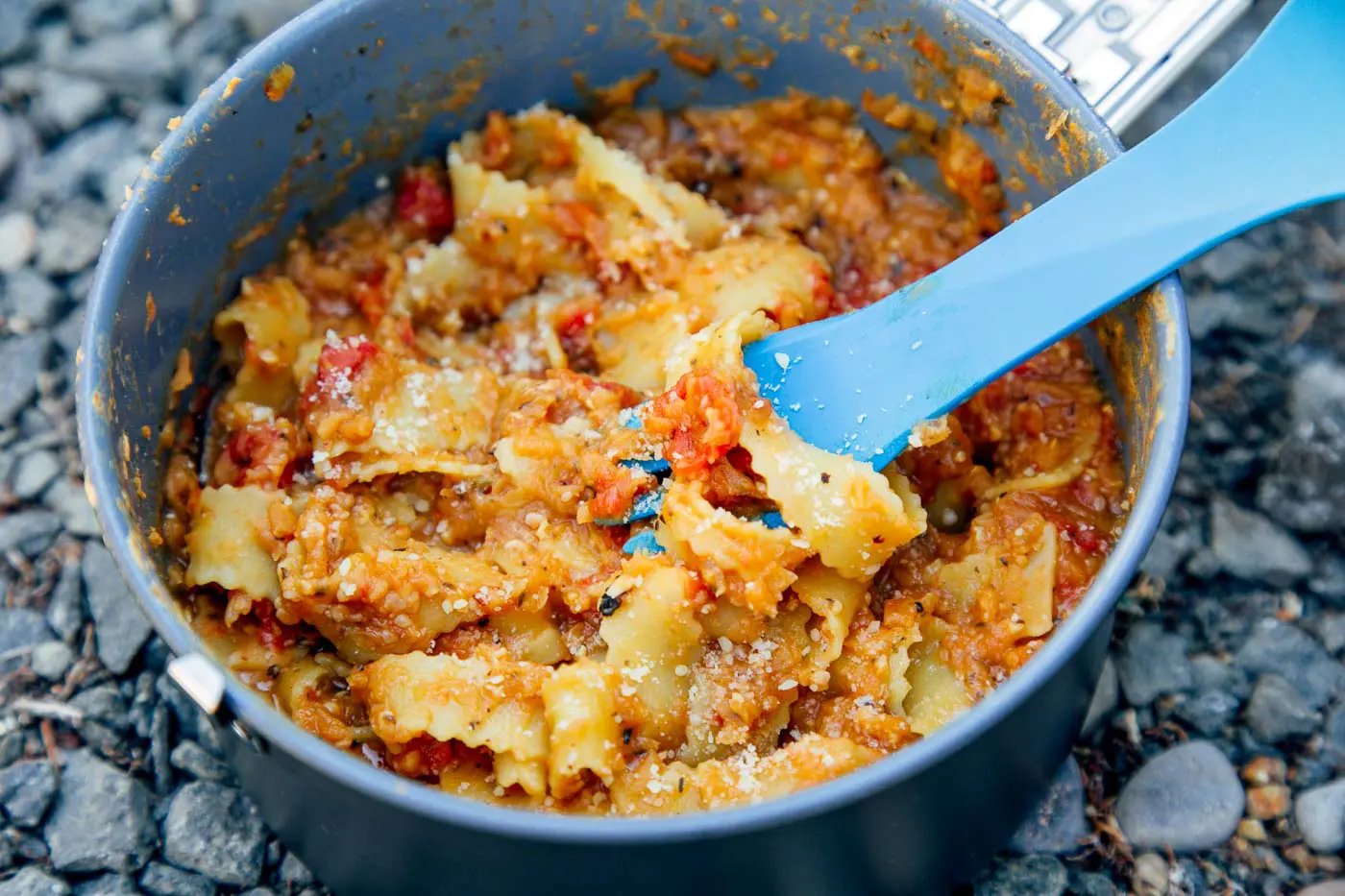 Red lentil marinara and pasta in a backpacking pot with a blue spoon