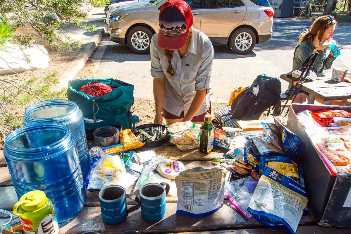Megan sorting through backpacking food that is spread out on a picnic table