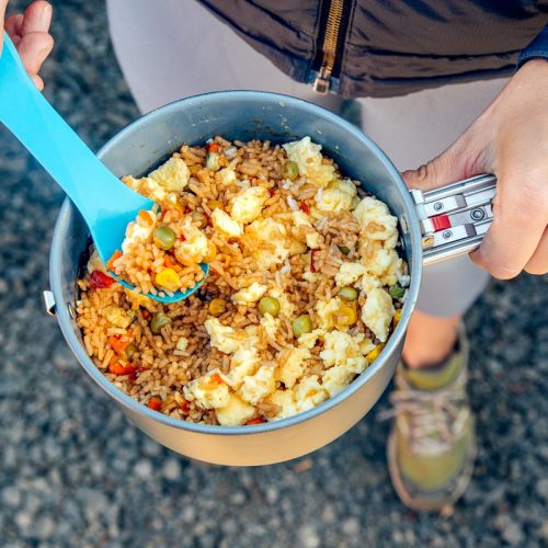 Megan holding fried rice in a backpacking pot