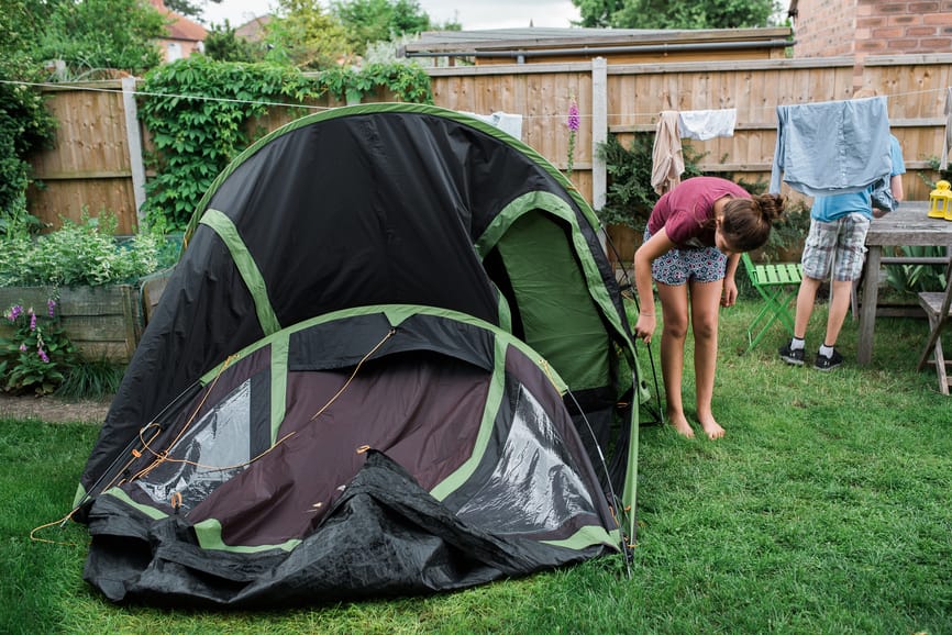 A girl setting up a tent in the backyard